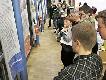 Die Betroffenheit steht ihnen ins Gesicht geschrieben: Die Besucher der Ausstellung vor einigen der 24 Plakate in der Aula am Friedrich-Rückert-Gymnasium. Fotos: Ralf Kestel