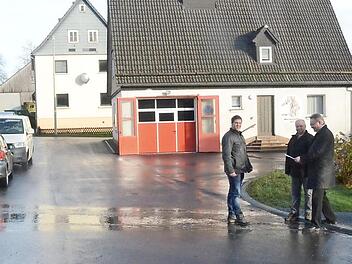 Sie freuen sich über die gelungene neue Wasserleitung und Straßendecke in Marienroth. Im Hintergrund sind das bisherige Feuerwehrhaus, mit neuem Tor versehen, und der neue Anbau (rechts) zu sehen (v. l.): Bauamtsleiter Andreas Schorn, Georg Fiedler, Bürgermeister Hans Pietz. Foto: K.- H. Hofmann