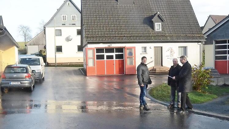 Sie freuen sich über die gelungene neue Wasserleitung und Straßendecke in Marienroth. Im Hintergrund sind das bisherige Feuerwehrhaus, mit neuem Tor versehen, und der neue Anbau (rechts) zu sehen (v. l.): Bauamtsleiter Andreas Schorn, Georg Fiedler, Bürgermeister Hans Pietz. Foto: K.- H. Hofmann