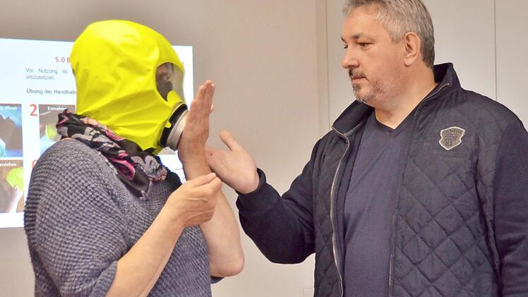 Ein kurzer Test genügt, um festzustellen, ob die Brandschutzhaube bei Birgit Metz wirklich richtig sitzt. Hier erklärt Brandschutzfachmann Joachim Dietz, wie sie das machen soll. Foto: Kathrin Kupka-Hahn