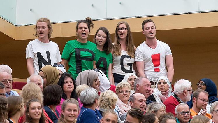 F&uuml;nf Zuh&ouml;rer mit T-Shirts mit der Aufschrift "No PAG!" protestieren vom Zuschauerrang im Plenarsaal des bayerischen Landtags aus gegen das Polizeiaufgabengesetz (PAG). Foto: Peter Kneffel/dpa