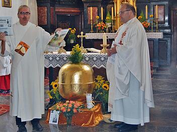 Diakon Christoph Glaser mit einer Saale-Zeitung und dem Würzburger Sonntagsblatt, die mit anderen Dokumenten und Münzen in die Turmkugel kommen; rechts: Pfarrer Gerd Greier vor der Segnung der Turmkugel.  Foto: Sigismund von Dobschütz