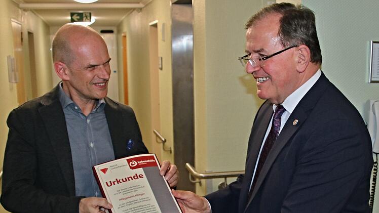 Bezirkstagspräsident Erwin Dotzel (rechts) überreicht an Heimleiter Christian Wokel die Urkunde für das Pflegeheim Klinger, mit der das Engagement der Einrichtung für die Einstellung von Behinderten gewürdigt wird.  Fotos: Helmut Will