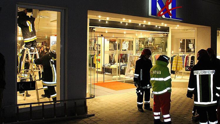 Aus der Zwischendecke des Bekleidungsgeschäftes drang Rauch in die Geschäftsräume. Die Feuerwehr öffnete die Decke (links). Foto: Ulrike Nauer