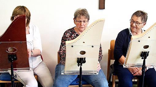 Auf dem Foto von links: Saiten-Klang-Spielerin Edeltraud Milner. Ursula Ziegler aus dem Diebacher Team versucht sich unter Anleitung an der Veeh Harfe. Und neben ihr Saiten-Klang-Spielerin Monika Hofmann.