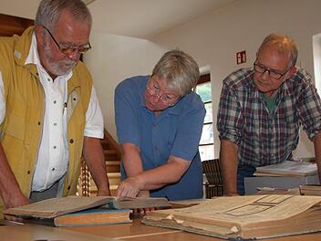 Dieter Rothkegel (von links), Gisela Salzmann und Matthias Dittmayer wälzen alte Zeitungsbände in der Stadtbibliothek. Annoncen ehemaliger Geschäfteinhaber der Ludwigstraße wecken ihr besonderes Interesse. Foto: Ulrike Müller