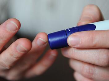 Eine Frau benutzt eine Stechhilfe f&uuml;r die Blutzuckermessung