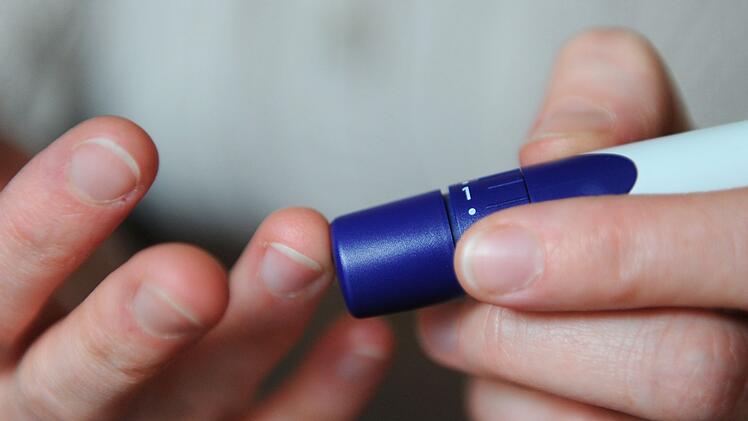 Eine Frau benutzt eine Stechhilfe f&uuml;r die Blutzuckermessung