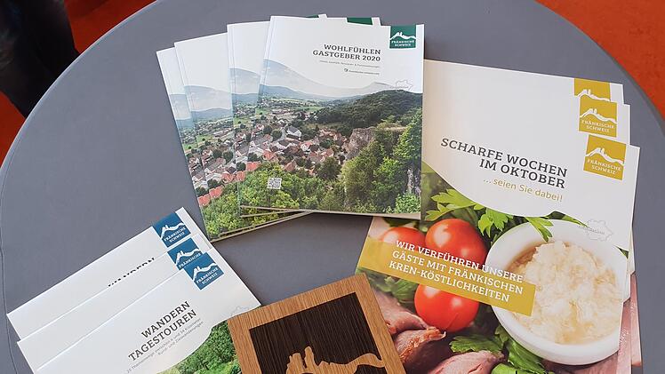 Erste Broschüren und Plakate sowie das Partnerlogo auf Holz