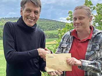 Pfarrerin Sonja von Aschen überreicht Burghard Schunkert einen Scheck mit den gesammelten Spendengeldern.