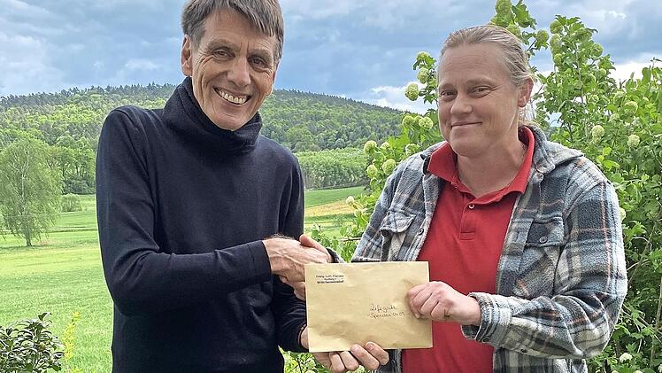 Pfarrerin Sonja von Aschen überreicht Burghard Schunkert einen Scheck mit den gesammelten Spendengeldern.