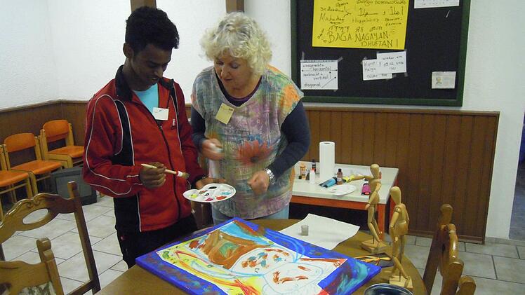 Helga Weißenberger erklärt einem jungen Workshop-Teilnehmer die richtige Maltechnik. Foto: Julia Raab