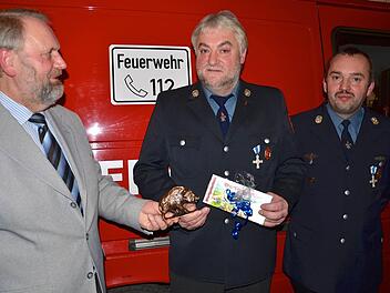Bürgermeister Franz Josef Kraus und Feuerwehr-Vorsitzender Markus Sponsel überreichen Heinrich Sponsel Geschenke.  Foto: wro