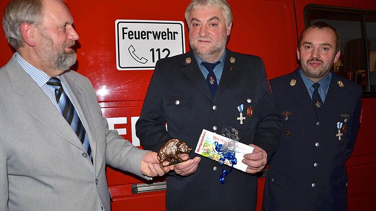 Bürgermeister Franz Josef Kraus und Feuerwehr-Vorsitzender Markus Sponsel überreichen Heinrich Sponsel Geschenke.  Foto: wro