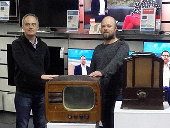 Junge Chefs mit historischen Geräten: Ralph und Mathias Knüttel (rechts) holen immer wieder einmal den alten Fernseher und das urige Radio hervor. Beide Objekte stammen noch aus der Anfangszeit des Bad Brückenauer Traditionsunternehmens. Foto: Rolf Pralle