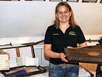 Peter Becker (rechts) überreicht an Vorsitzende Bettina Rubel (Mitte) einen besonderen Schatz: Die Zither aus dem Jahr 1889 und die Noten aus dem Jahr 1884, die Lucina Spitzenpfeil entgegennehmen durfte, sind ein weiteres historisches Highlight im kleinen Heimatmuseum in der Zecher-Halle in Neukenroth. Foto: Joachim Beez