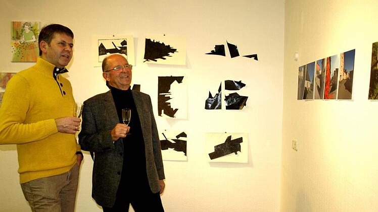 Bernd Daum (li) und Otmar Adler in Betrachtung der Fotos von Martin Schlenger versunken.