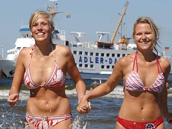 Elise (l.) und Anja genießen am Strand des Ostseebades Ahlbeck auf der Insel Usedom den Sommer. Die hochsommerliche Hitze deutlich über 30 Grad soll weiter anhalten. Foto: Stefan Sauer dpa/mv