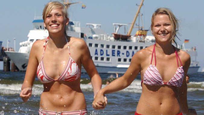 Elise (l.) und Anja genießen am Strand des Ostseebades Ahlbeck auf der Insel Usedom den Sommer. Die hochsommerliche Hitze deutlich über 30 Grad soll weiter anhalten. Foto: Stefan Sauer dpa/mv