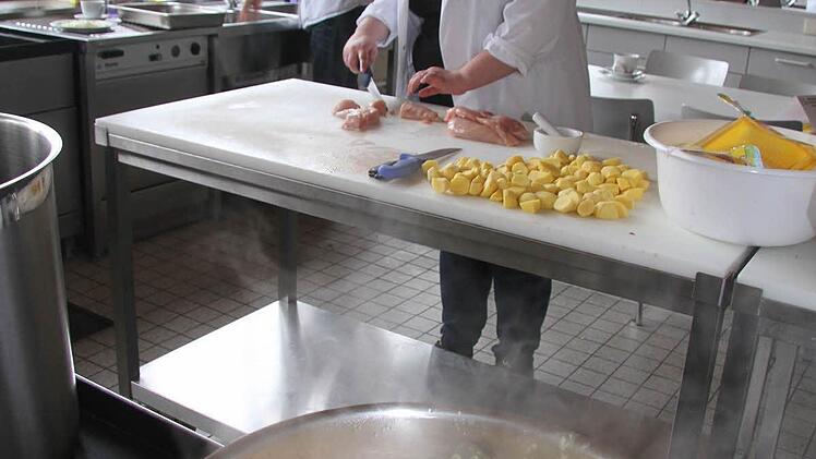 Auberginen, Paprika, Tomaten und Kokosmilch köcheln als Beilage für das Hähnchencurry vor sich hin - im Hintergrund bereitet Tina Wagner (18) die Hähnchenteile zu.