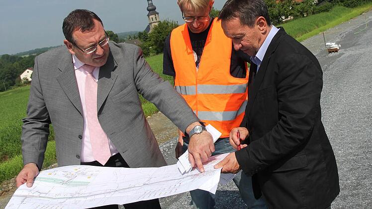 Siegfried Beck vom Bauamt, Jörg Döhler von der Baufirma Rädlinger und Bürgermeister Norbert Gräbner (von links) an der Baustelle bei Seibelsdorf. Im Hintergrund wird am neuen Gehweg gearbeitet.