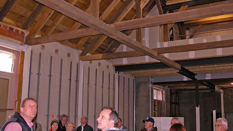 Interessierte Bürger, Bürgermeister Michael Keilich (links), Altbürgermeister Rainer Marr und der Bauausschuss ließen sich vom Architekten Harald Gasmann Fortschritte beim Domänenumbau erläutern. Von der künftigen Veranstaltungshalle aus schafft die erhalten gebliebene Dachkonstruktion freie Sicht bis unters Dach. Foto: Klaus Oelzner