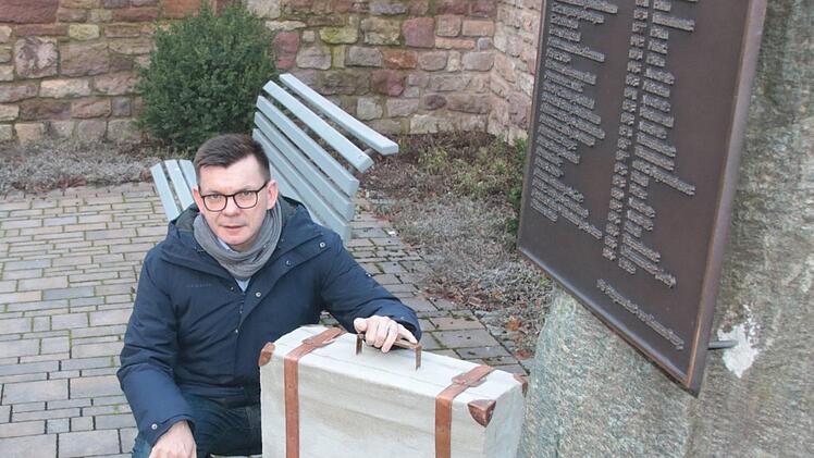 Bürgermeister Armin Warmuth mit dem Koffer aus Metall und Beton, der am Seelhausplatz in der Hammelburger Innenstadt bereits aufgestellt ist. Foto: Ralf Ruppert