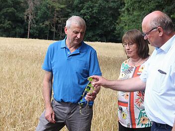Landwirt Günter Fensel (li.) klärt Horst Krehn, Leiter des Landwirtschaftsamts, sowie die stellvertretende Landrätin Gabriele Klaußner über seine Ernteerträge auf.Hendrik Kowalsky