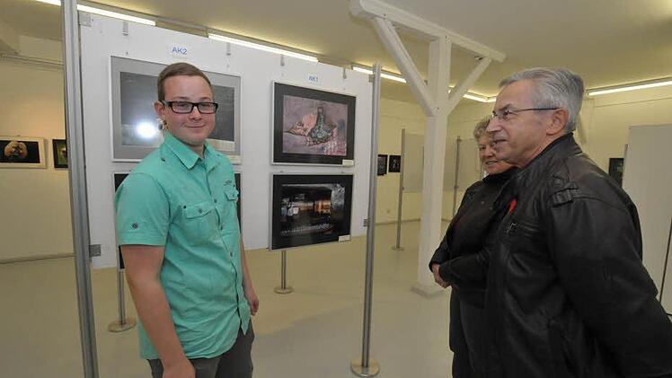 Preisträger Jan Hendrik Bier steht vor seinem Siegerbild und spricht mit Besuchern.