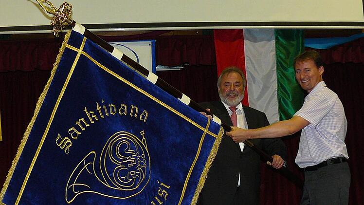 Die Fahne für die St. Iwaner Blasmusik, die Norbert Volk (links) an Fahnenträger Zsolt Spannberger übergibt.