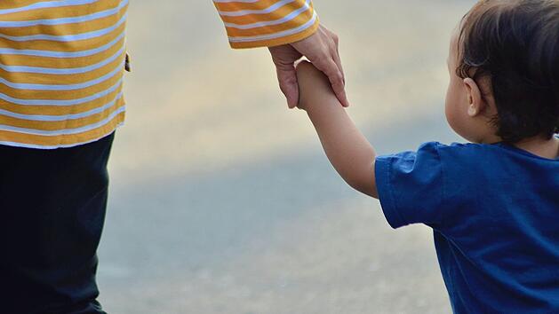 Mutter h&auml;lt Kleinkind an der Hand