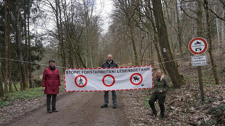 Das große Sperr- und Warnschild am Eingang zum Liesbachtal wurde in den  vergangenen Wochen von Spaziergängern und Wanderern nicht immer ernst  genommen und beachtet. Schönaus Bürgermeisterin Sonja Rahm (von links), Forstbetriebsleiter   Michael Kutscher (Bayerische Staatsforsten Bad Brückenau) und  Försterin Freya  Storath bitten dringend um Rücksichtnahme. Die Sperrung  wird voraussichtlich bis Juni diesen Jahres noch notwendig sein. Foto:  Marion Eckert