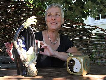 Das Fertigen von Urnen ist eine Ausnahme. Hier interpretiert die Künstlerin Barbara Gröhling zwei ihrer "normalen" Kunstwerke: links eine ungewöhnliche Krippe mit Wänden aus gefalteten Händen, rechts einen Würfel mit den Symbolen der sechs großen Weltreligionen.  Foto: Katja Kölbl