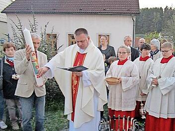 Pfarrer Michal Osak festigt Symbole auf die Osterkerze.