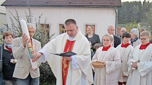Pfarrer Michal Osak festigt Symbole auf die Osterkerze.