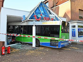 Bus kollidiert mit Auto und kracht in Reisebüro