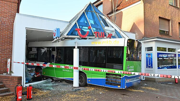 Bus kollidiert mit Auto und kracht in Reisebüro