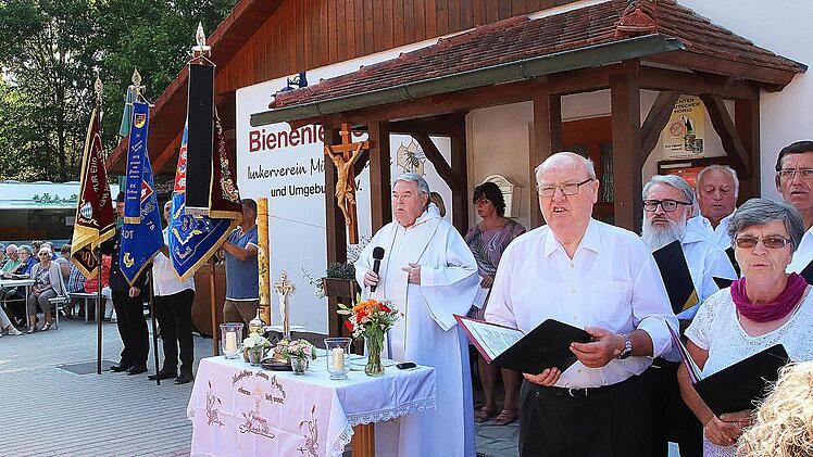 Den Gottesdienst bei der Ambrosiusfeier am Bienenhaus zelebrierte Augustinerpater Winfried Pfeuffer (Mitte). Die Liedertafel gab dem Gottesdienst einen feierlichen Rahmen. Auch eine Fahnenabordnung war dabei. Foto: Dieter Britz
