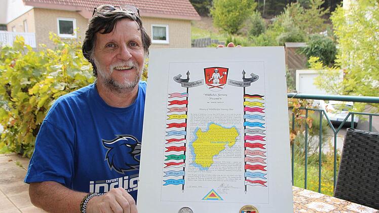 Erinnerungen an eine schöne Zeit: Robert Gridley zeigt die Urkunde und die zwei Auszeichnungen, die ihm verliehen wurden. Neben der Geschichte des Truppenübungsplatzes sind auch alle Einheiten abgebildet, die jemals in Wildflecken stationiert waren.  Foto: Sebastian Vogt