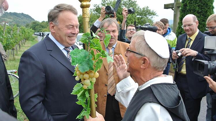 Die Silvaner- und Wein-Symbolfigur Abt Degen alias Richard Schlegelmilch aus Zeil gehörte beim hochoffiziellen Ministerbesuch dazu. Überhaupt wenn die Weinlage, auf der Helmut Brunner (links) den ersten Träubel abschnitt, der Steinbacher Nonnenberg ist. Mit im Bild sind die beiden Vorsitzenden des Abt-Degen-Weintals, die beiden Bürgermeister Bernhard Ruß (Sand, Mitte) und Thomas Stadelmann (Zeil, rechts).