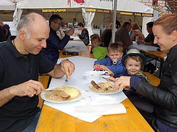 Domenico und Katharina Marano lassen sich die Klöße mit Fleisch und Bratwurst schmecken. Ihr Sohn Alexandro (mit Hut) und sein Kindergartenfreund Noel schauen zu. Foto: Helke Renner