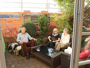 Bernhard Köppl, Gisela Rogatti, Ulrike Köppl und Petra Löblein sitzen auf der Terrasse des Hauses Würzburger Straße 4a. Dahinter erhebt sich der Neubau, gegen dessen Genehmigung durch die Stadt sie klagen. Foto: Barbara Herbst
