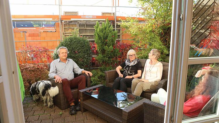 Bernhard Köppl, Gisela Rogatti, Ulrike Köppl und Petra Löblein sitzen auf der Terrasse des Hauses Würzburger Straße 4a. Dahinter erhebt sich der Neubau, gegen dessen Genehmigung durch die Stadt sie klagen. Foto: Barbara Herbst