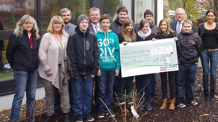 Das Projekt "Futurino" von "Persil" unterstützt die Küpser Schule mit 6500 Euro. Darüber freuen sich in der "Naschstraße" Henkel-Mitarbeiter Georg Hattel (dritter von rechts), Bürgermeister Herbert Schneider (fünfter von links) sowie Schulleitung und Lehrkräfte  mit einigen Neuntklässlern, die die Bäume mit gepflanzt hatten.