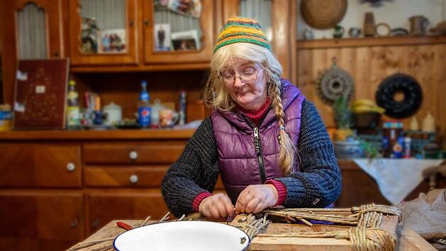 Das Arbeitszimmer dient auch als Wohnraum und als K&uuml;che. Hier flicht Helga Prommer ihre Korbwaren. Dazu geh&ouml;ren auch Reparaturarbeiten. Aktuell ist sie damit besch&auml;ftigt, die Sitzfl&auml;che eines Stuhls aus Binsen zu fertigen.  Foto: Klaus Gagel