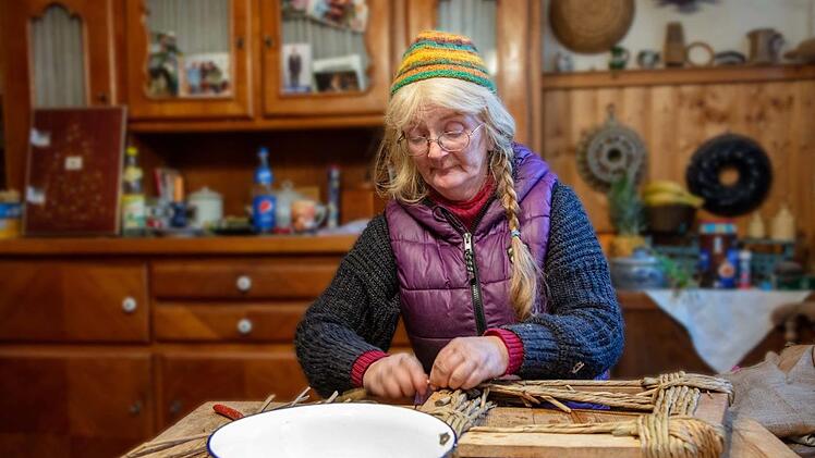 Das Arbeitszimmer dient auch als Wohnraum und als Küche. Hier flicht Helga Prommer ihre Korbwaren. Dazu gehören auch Reparaturarbeiten. Aktuell ist sie damit beschäftigt, die Sitzfläche eines Stuhls aus Binsen zu fertigen.  Foto: Klaus Gagel