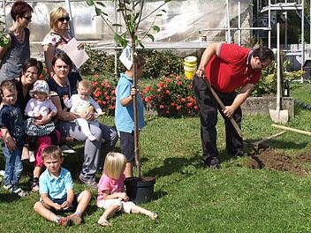 Jörg Deuerling gräbt das Loch für den Mirabellenbaum seiner Tochter Jule. Von links stehend Rita und Christiane Gareis vom Gartenbauverein, sitzend Sabine Schuberth mit Sohn Bastian und Tochter Johanna, Nadine Deuerling mit Tochter Jule und die Söhne Jonas (stehend) und Jan.  Foto: privat