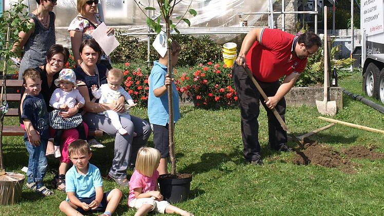 Jörg Deuerling gräbt das Loch für den Mirabellenbaum seiner Tochter Jule. Von links stehend Rita und Christiane Gareis vom Gartenbauverein, sitzend Sabine Schuberth mit Sohn Bastian und Tochter Johanna, Nadine Deuerling mit Tochter Jule und die Söhne Jonas (stehend) und Jan.  Foto: privat