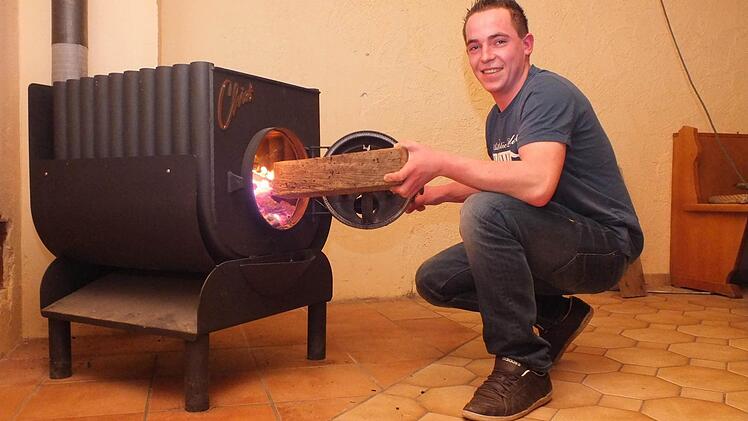 Vorsitzender Matthias Grom befeuert den neuen Ofen. Im Jugendheim kann man sich nun auch treffen, wenn es draußen kalt ist. Foto: Björn Hein