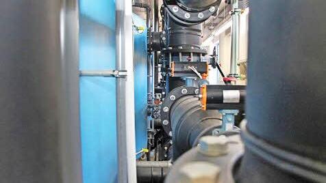 Lange schwarze Rohre leiten das Wasser in die blauen Filtertanks. Foto: Thomas Heuchling